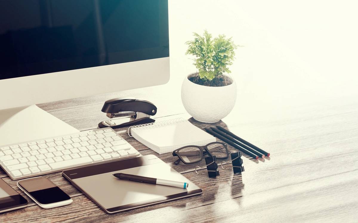 A desk with a laptop, journal and a plant